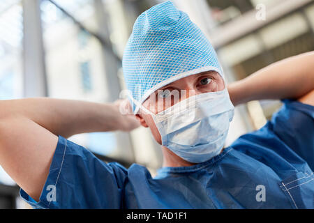 Arzt als Chirurg in der Notaufnahme in Blau OP-Bekleidung mit Mundschutz und Haube Stockfoto