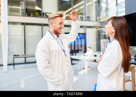 Junge Arzt macht Small Talk mit eine asiatische Frau Arzt in einem Forschungsprojekt Stockfoto