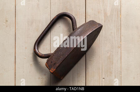Alte rostige Bügeleisen liegt auf Holztisch, Ansicht von oben. Nahaufnahme mit selektiven Fokus Stockfoto
