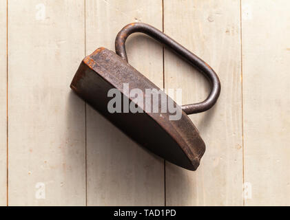 Alte rostige Bügeleisen liegt auf einem grauen Holz- Tabelle, Ansicht von oben. Nahaufnahme mit selektiven Fokus Stockfoto