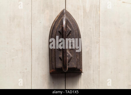 Alte rostige Bügeleisen steht auf einem grauen Holz- Tabelle, Ansicht von oben. Nahaufnahme mit selektiven Fokus Stockfoto