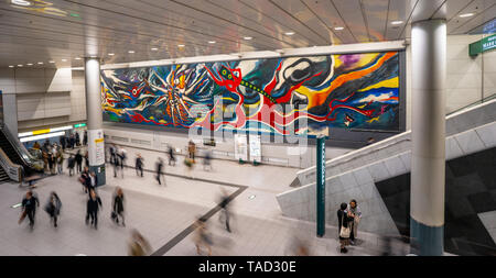 Der Mythos Von Morgen: Taro Okamotos Wandbild In der Station Shibuya mit verschwommenen Menschen, die umherlaufen. Tokio, Japan. Anschuldigung der Atombombenabwürfe Stockfoto