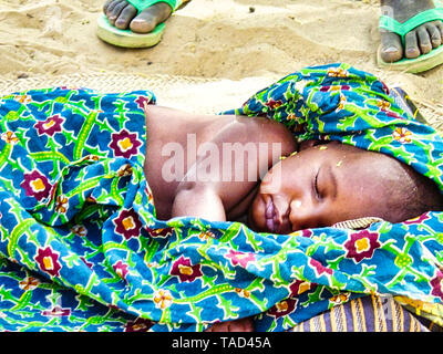 TIMBUKTU, MALI - Februar Circa, 2019. Nicht identifizierte armes Baby zur Festlegung auf schmutzigen Boden zu schlafen. Menschen brauchen Hilfe. Konzept für Armut oder hunge Stockfoto