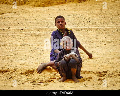 TIMBUKTU, MALI - Februar circa, 2019. Nicht identifizierte zwei Kind jugendlich Jungen in der Wüste stehen mit frindship, in die Kamera schaut. Sehr armen ländlichen Kid. Stockfoto