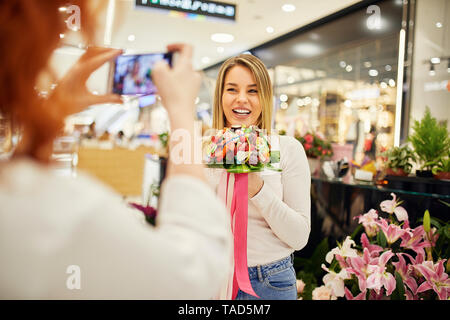 Happy woman holding Candy Bouquet in einem Shop für ein Foto posiert Stockfoto