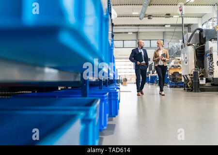 Kaufmann und Kauffrau wandern und sprechen in der Factory Stockfoto