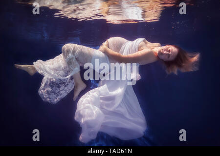 Schwangere Frau tragen weiße Kleid unter Wasser Stockfoto