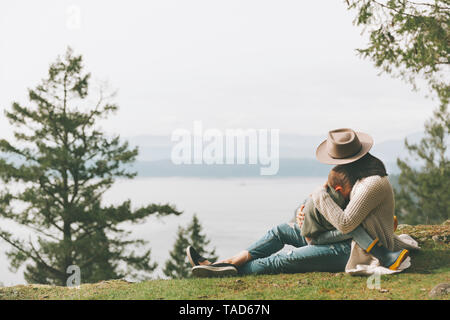 Mutter sitzt auf Gras, ihr Sohn kuscheln in der Natur Stockfoto