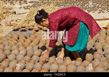 Frau drehen Tongefäße, da sie Sun-dry in Kumale Tol (Töpfern, Keramik), Bhaktapur, Tal von Kathmandu, Nepal Stockfoto