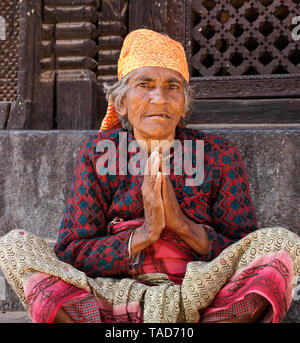 Ältere Frau sitzend mit Handflächen in namaste Gruß, Bhaktapur, Tal von Kathmandu, Nepal Stockfoto