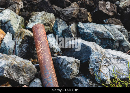 Rusty Abfluss Rohr oben auf Granit Steine bei Tageslicht Stockfoto