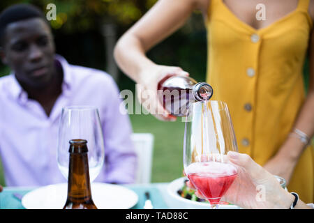 Host gießen Wein in die Gläser zu einem Sommer Abendessen im Garten Stockfoto