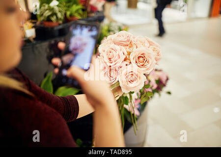 In der Nähe von Frau mit Bündel Rosen in Flower Shop ein Handy Bild Stockfoto