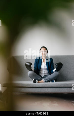 Porträt der jungen Frau sitzt auf der Couch Boxhandschuh Stockfoto