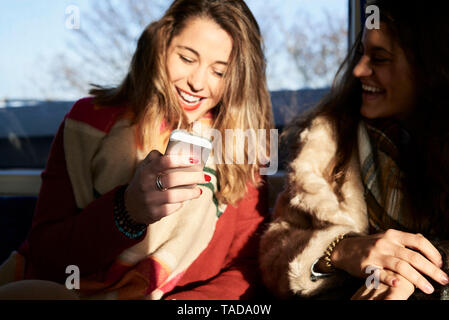 UK, London, zwei glückliche Frauen in der U-Bahn mit Handy Stockfoto