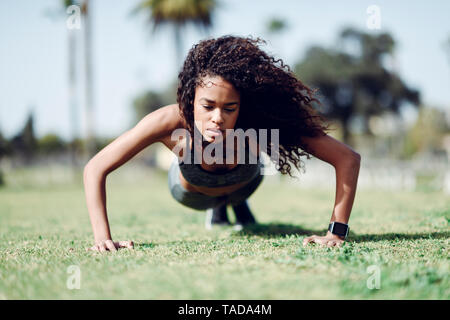 Sportliche junge Frau, Push-ups auf Rasen Stockfoto