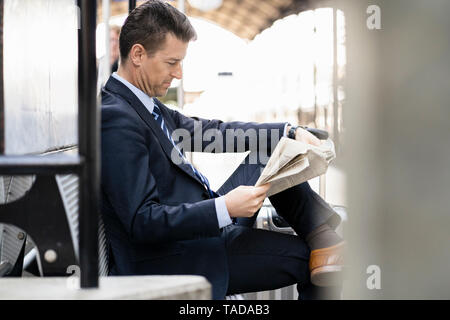 Geschäftsmann lesen Zeitung auf Bahnsteig Stockfoto