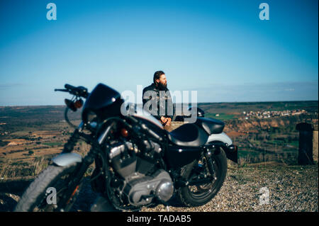 Mann mit custum Motorrad mit einer Unterbrechung bei Sonnenuntergang Stockfoto