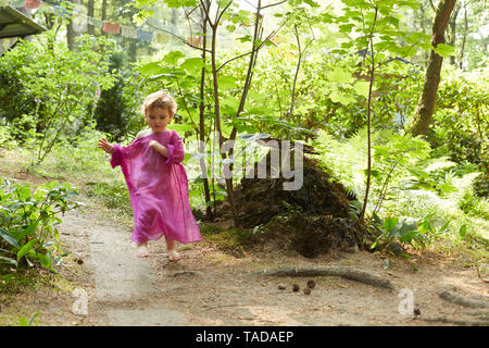 Kleines Mädchen mit rosa Tunika laufen in der Natur Stockfoto