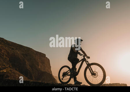 Spanien, Lanzarote, Mountainbiker auf einer Reise bei Sonnenuntergang