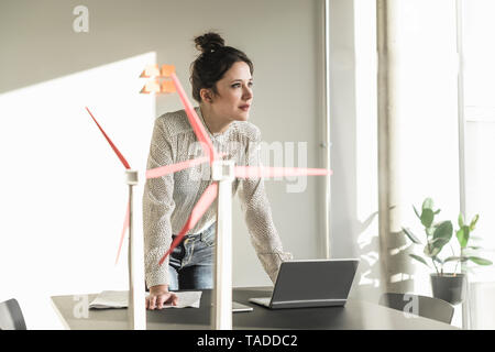 Geschäftsfrau mit wind turbine Modelle und Laptop auf dem Schreibtisch im Büro Stockfoto