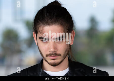 Portrait von gut aussehenden bärtigen Mann in modische Kleidung auf der Straße gegen blure Hintergrund gekleidet. Stattliche hipster Kerl auf der Straße darstellen. Stockfoto
