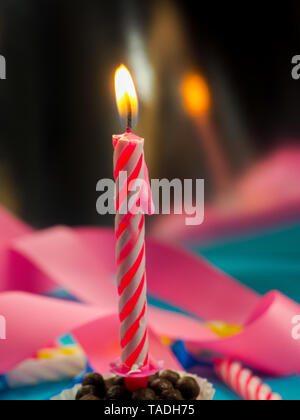 Kerze zum Geburtstag Brennen im Hintergrund andere Kerzen, rosafarbenen Bändern, festliche Atmosphäre Stockfoto