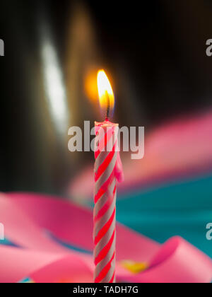 Kerze zum Geburtstag Brennen im Hintergrund andere Kerzen, rosafarbenen Bändern, festliche Atmosphäre Stockfoto