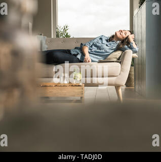 Glückliche Frau auf der Couch zu Hause liegen Stockfoto