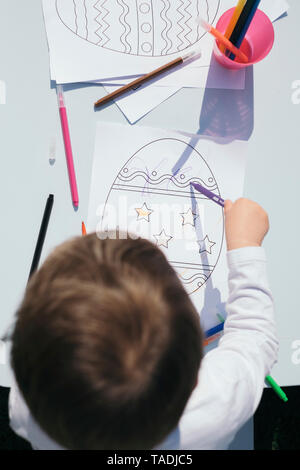 Blick von oben auf die Toddler färben Ostereier auf dem Papier Stockfoto