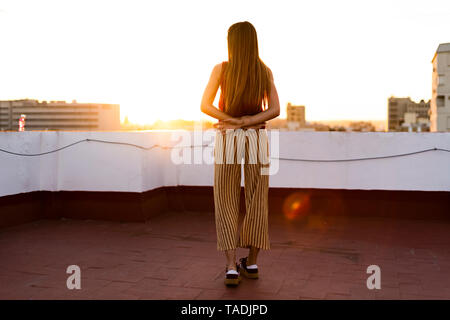 Ansicht der Rückseite des Teenager stehen auf der Dachterrasse in der Stadt bei Sonnenuntergang Stockfoto