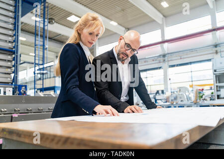 Kaufmann und Kauffrau auf der Suche nach Plan auf dem Tisch in der Factory Stockfoto