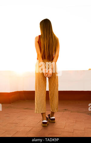 Ansicht der Rückseite des Teenager stehen auf dem Dach Terrasse bei Sonnenuntergang Stockfoto