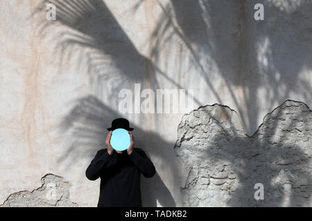 Marokko, Essaouira, Mann, eine Melone holding Spiegel vor sein Gesicht an der Wand Stockfoto