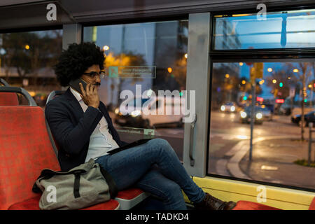 Spanien, Barcelona, Geschäftsmann, der in einer Straßenbahn auf dem Mobiltelefon Stockfoto