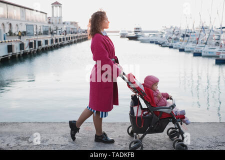 Mutter, Tochter im Kinderwagen an einem Jachthafen Stockfoto