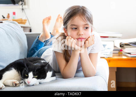 Porträt von kleinen Mädchen auf der Couch liegend mit Katze Stockfoto