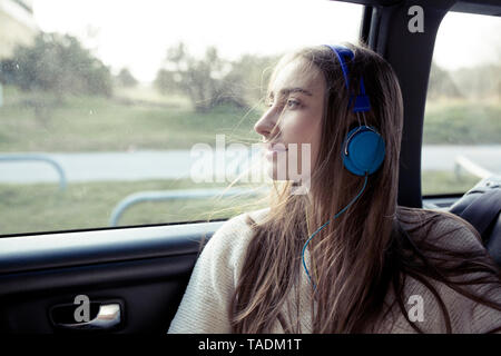 Junge Frau mit windswept Haar in einem Auto Kopfhörer tragen Stockfoto