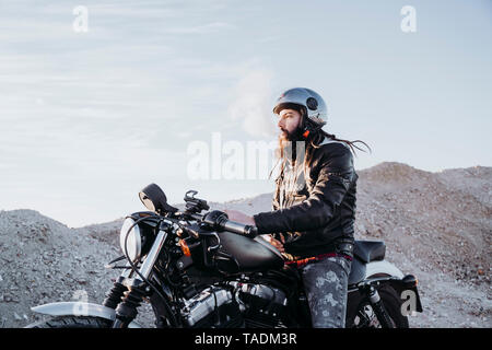 Mann mit Dreadlocks sitzen auf dem Motorrad rauchen Elektronische Zigarette Bärtigen Stockfoto