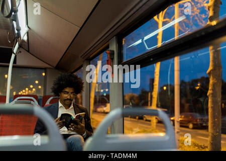Spanien, Barcelona, Geschäftsmann, der in einer Straßenbahn in der Nacht ein Buch lesen Stockfoto