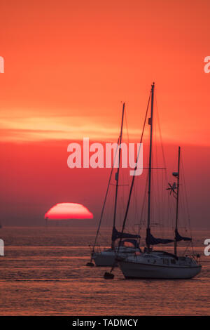 Saharastaub verursacht den Himmel mehr rote als üblich in den nächsten Tagen aufgrund einer Staubwolke in Luft aus Nordafrika zu suchen. Hier ist die Sonne gesehen steigende Auf der Themse hinter Schiffen in Gravesend. Mit: Atmosphäre, wo: Gravesend, Großbritannien Wann: 23 Apr 2019 Credit: WENN.com Stockfoto