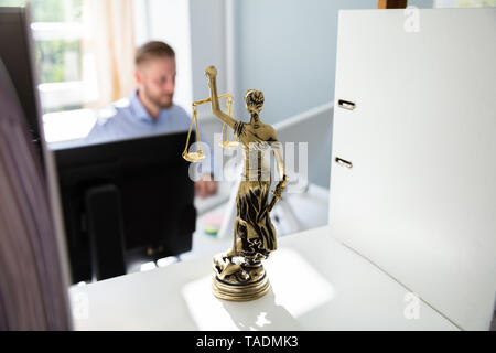 Gerechtigkeit Statue auf Regal und Anwalt Arbeiten im Büro im Hintergrund Stockfoto