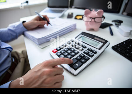 Nahaufnahme der Kaufmann Hand Berechnung Bill mit dem Rechner im Büro Stockfoto