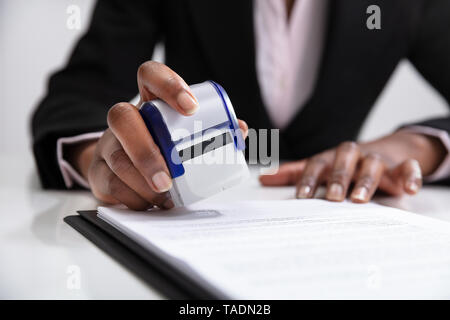 Nahaufnahme der Geschäftsfrau Stempel setzen auf Dokumente im Büro Stockfoto