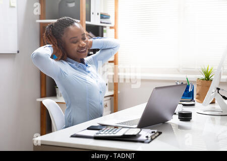 Happy Geschäftsfrau streckte seine Arme, während Sie am Laptop im Büro Stockfoto