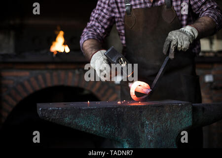 Nahaufnahme der Schmied mit Hammer am Amboss in seiner Werkstatt Stockfoto