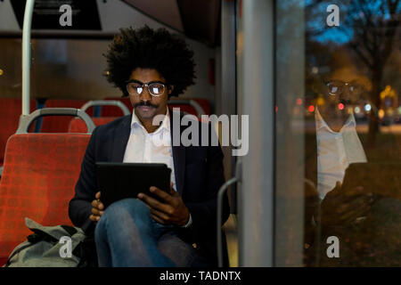 Spanien, Barcelona, Geschäftsmann, der in die Straßenbahn bei Nacht mit Tablet Stockfoto