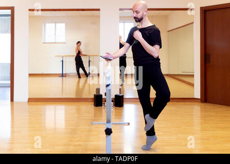 Ballet Dancer dehnen und über Handy in Ballett studio Stockfoto