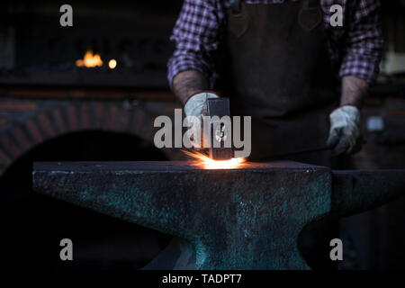 Nahaufnahme der Schmied mit Hammer am Amboss in seiner Werkstatt Stockfoto