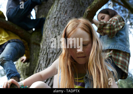 Rothaarige Mädchen mit Freunden klettern in einem Baum Stockfoto